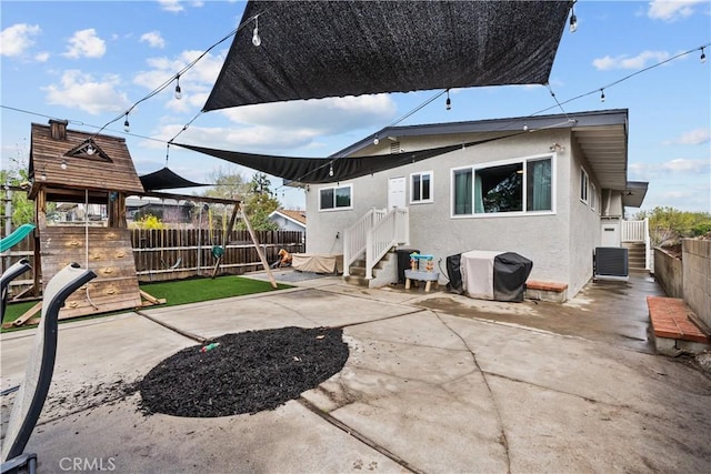 back of property featuring a patio, a playground, a fenced backyard, and stucco siding