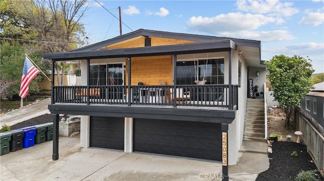 view of front of house with driveway, an attached garage, and stairs