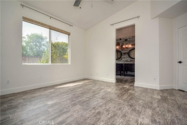 spare room featuring vaulted ceiling, baseboards, ceiling fan, and wood finished floors