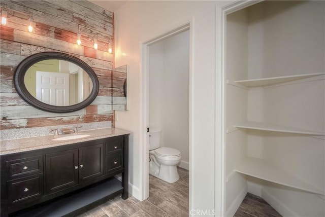 bathroom featuring toilet, vanity, and baseboards