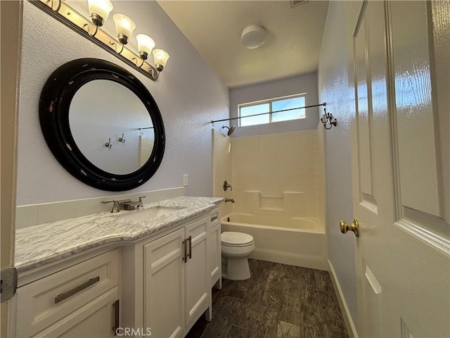 bathroom with vanity, wood finished floors, tub / shower combination, toilet, and a textured wall