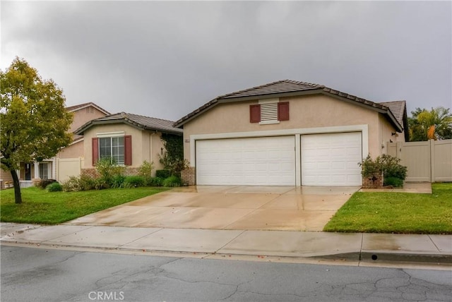 view of front of property featuring a front yard, fence, driveway, stucco siding, and a garage