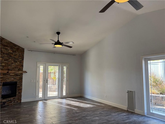 unfurnished living room featuring vaulted ceiling, a stone fireplace, ceiling fan, and wood finished floors