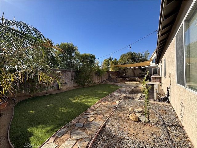 view of yard featuring a patio, a fenced backyard, and central AC