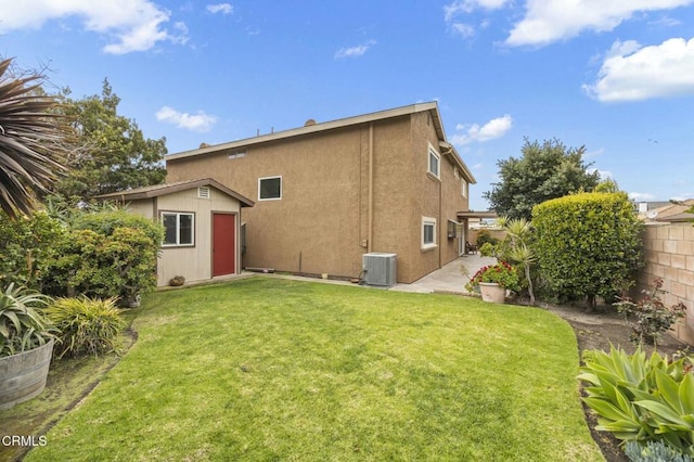 back of property featuring an outbuilding, a lawn, a fenced backyard, cooling unit, and a storage shed