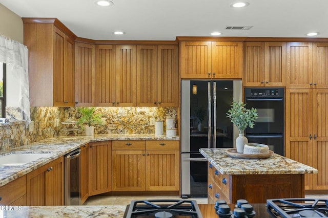 kitchen with black appliances, brown cabinets, visible vents, and a sink