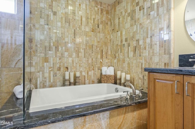 full bath with a garden tub, tile walls, and vanity