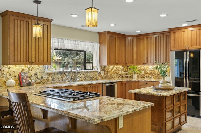 kitchen with light stone countertops, stainless steel gas cooktop, decorative backsplash, black fridge, and a peninsula