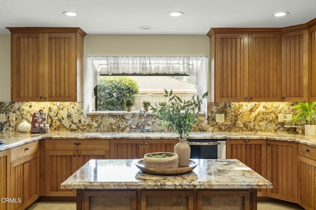 kitchen with stainless steel dishwasher, light stone counters, tasteful backsplash, and brown cabinets