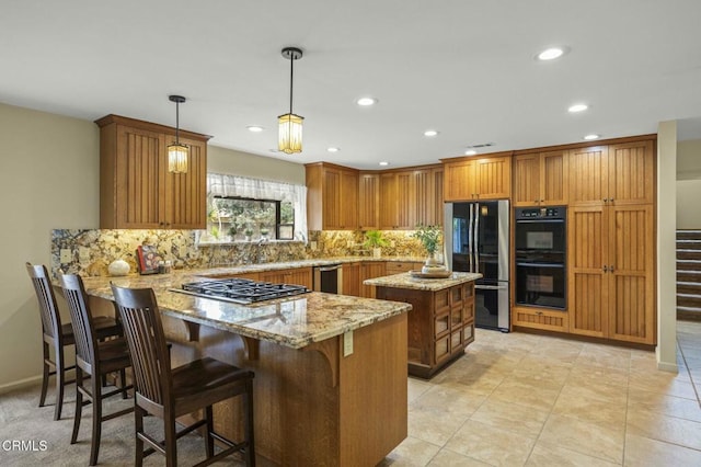 kitchen with backsplash, light stone counters, a peninsula, brown cabinetry, and black appliances