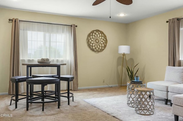 living area featuring a ceiling fan, baseboards, and carpet floors