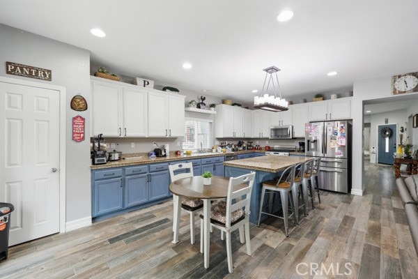 kitchen with blue cabinetry, white cabinetry, stainless steel appliances, and light wood-type flooring