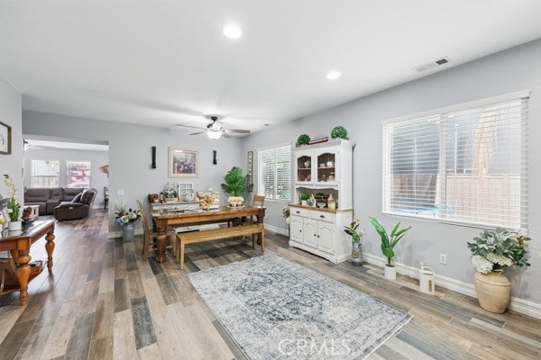 dining space with wood finished floors, visible vents, and baseboards