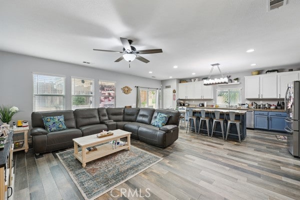 living area with visible vents, recessed lighting, a ceiling fan, and wood finished floors