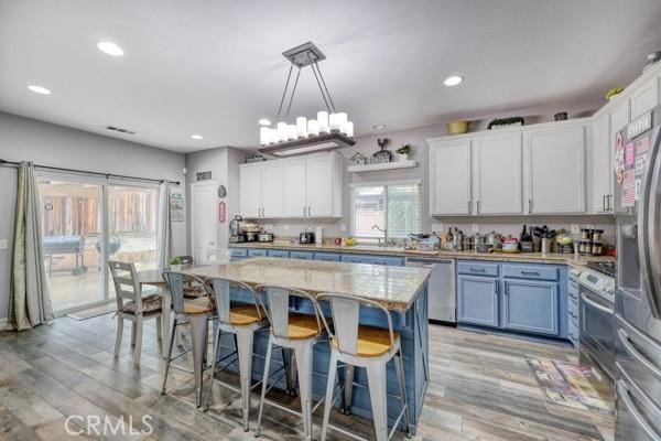 kitchen featuring a kitchen bar, white cabinets, light wood-style floors, and appliances with stainless steel finishes