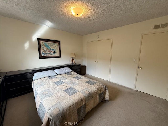 bedroom with a closet, visible vents, a textured ceiling, and carpet floors