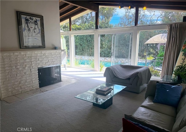 living area featuring lofted ceiling with beams, a brick fireplace, and carpet flooring