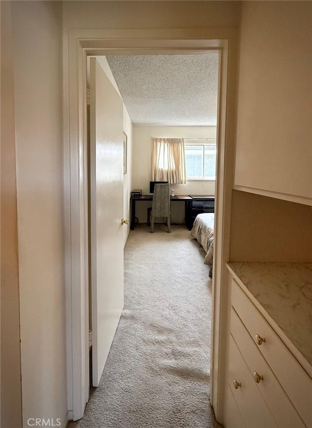 hall featuring light colored carpet and a textured ceiling