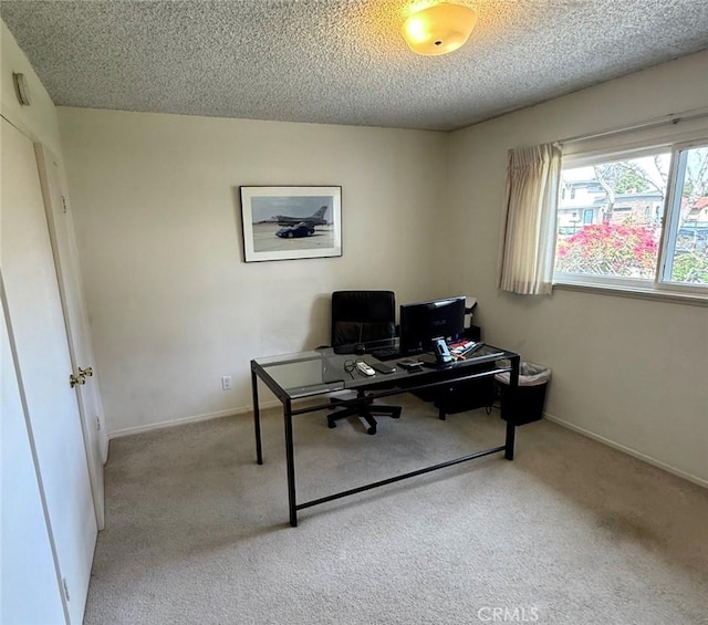 carpeted home office with a textured ceiling and baseboards