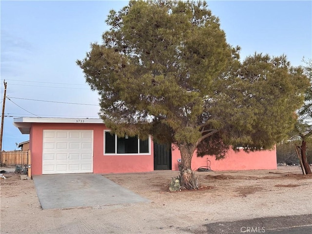 view of front of home with an attached garage, fence, and stucco siding