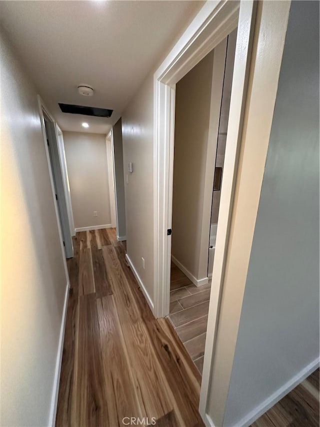 corridor with baseboards and wood finished floors