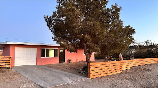 view of front of home featuring stucco siding, an attached garage, concrete driveway, and fence