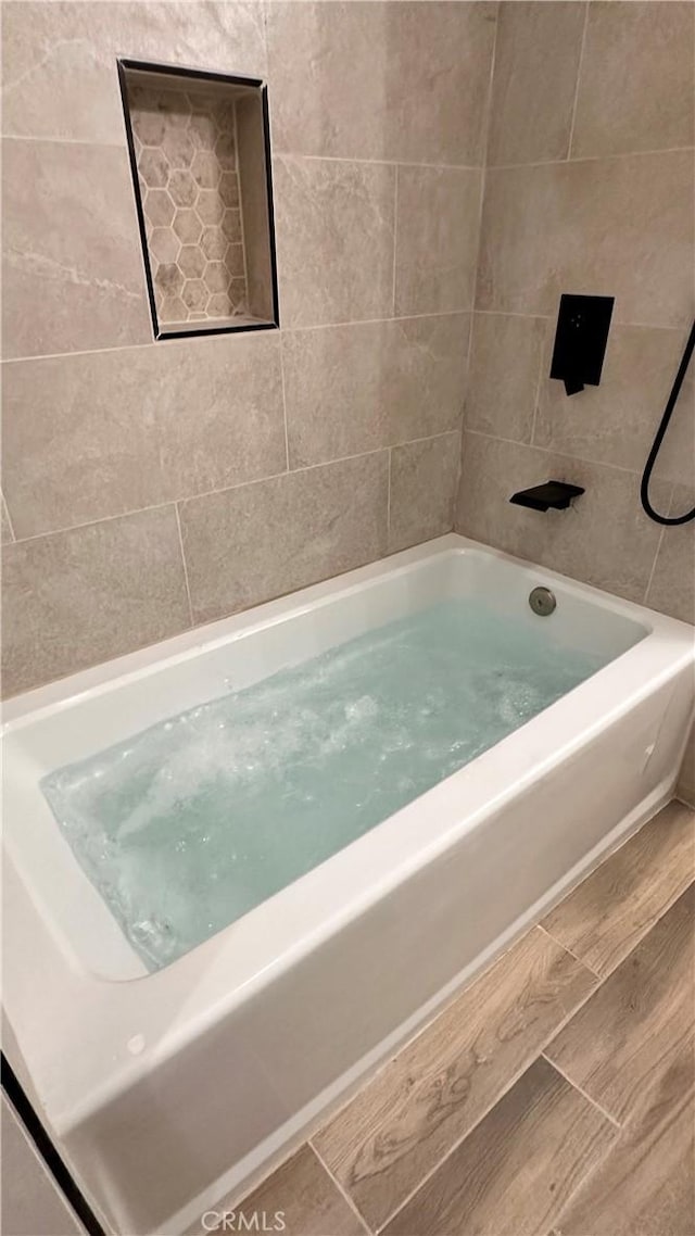 bathroom featuring wood finished floors and  shower combination