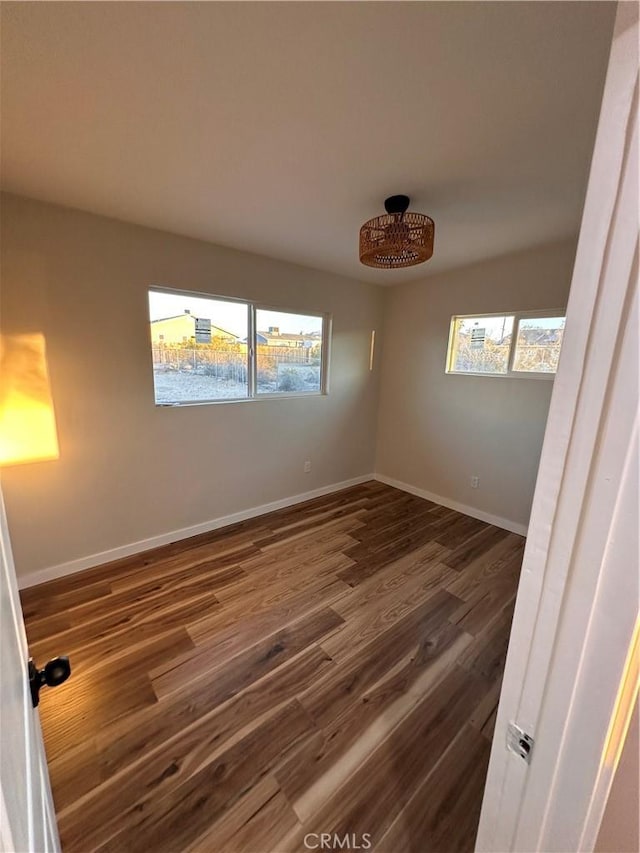 spare room featuring dark wood-style floors and baseboards