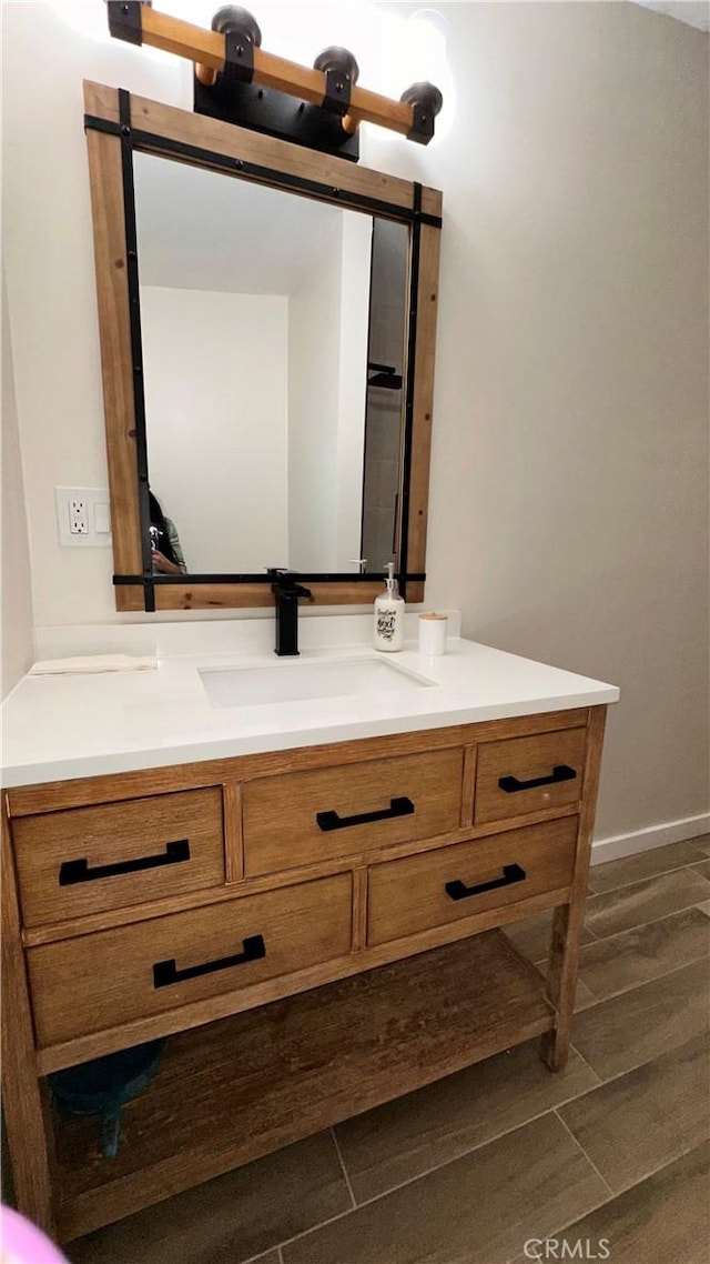 bathroom with baseboards, wood finished floors, and vanity