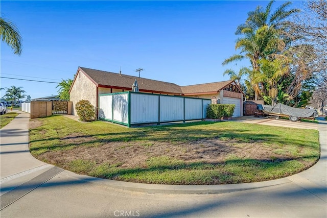 view of property exterior with a yard, stucco siding, a garage, and fence