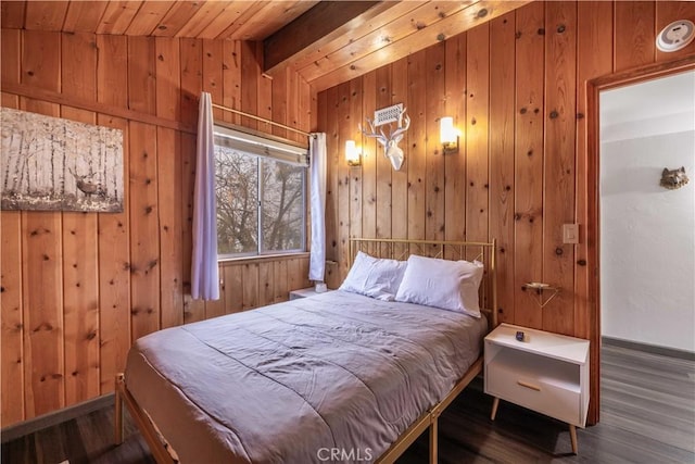 bedroom with lofted ceiling with beams, baseboards, wooden walls, and wood finished floors