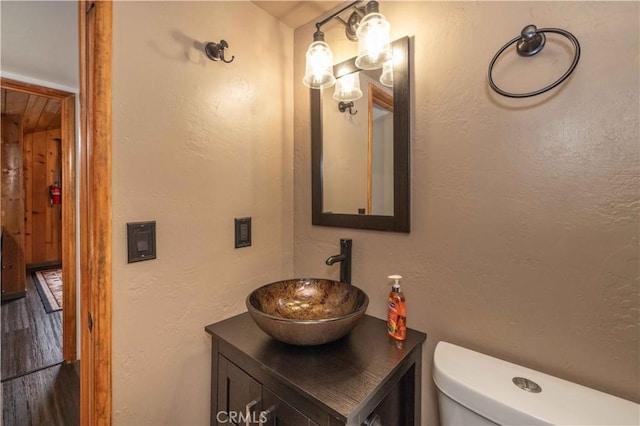 bathroom with toilet, vanity, and a textured wall