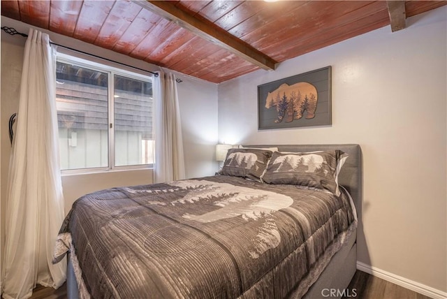 bedroom featuring beamed ceiling, wood ceiling, baseboards, and wood finished floors