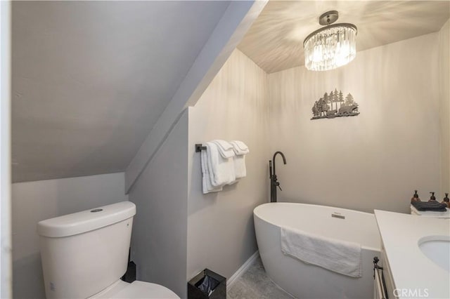 bathroom featuring vanity, a freestanding tub, toilet, and baseboards