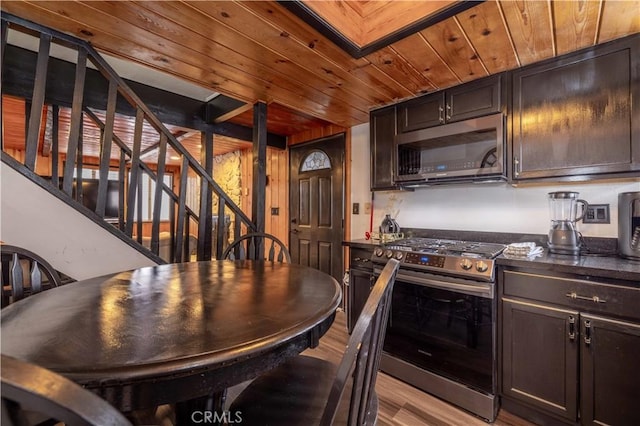 kitchen with dark brown cabinets, light wood-style flooring, appliances with stainless steel finishes, and wood ceiling