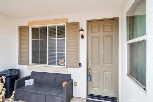 view of exterior entry featuring an outdoor living space and stucco siding