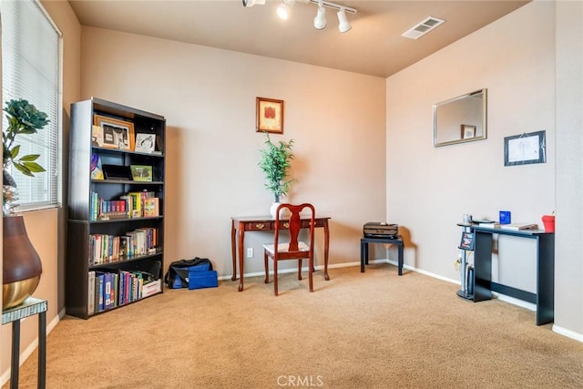 living area with visible vents, baseboards, carpet, and track lighting