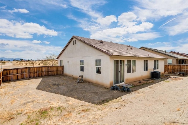 rear view of house featuring stucco siding, central AC unit, a tile roof, and fence