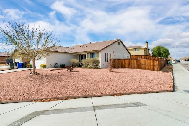 view of front of home featuring fence, an attached garage, stucco siding, concrete driveway, and a tile roof