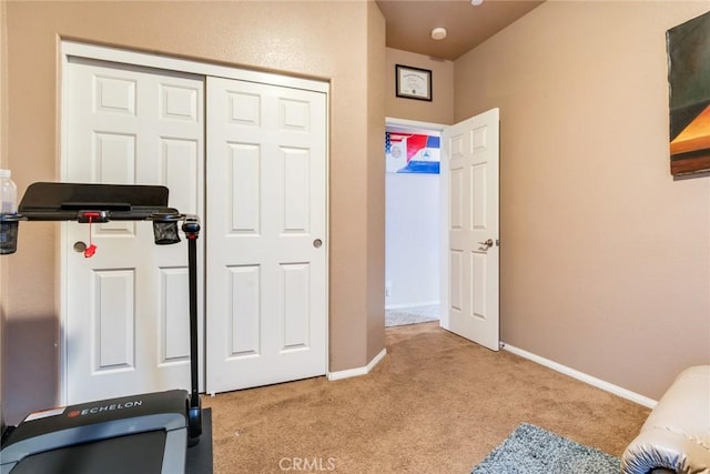 workout area with baseboards and light carpet