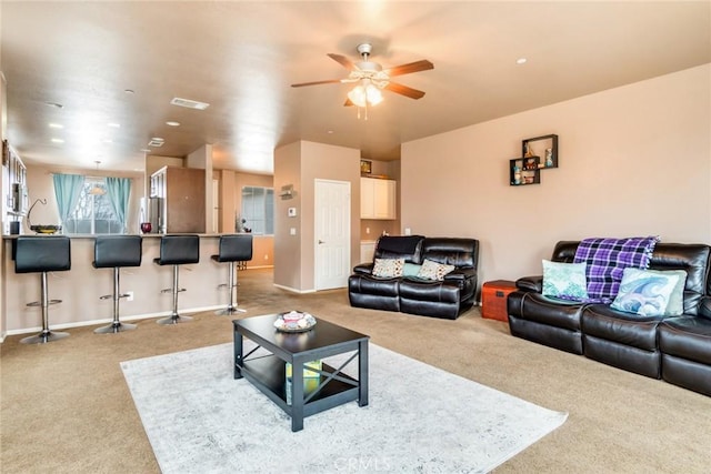 living room with visible vents, baseboards, light colored carpet, and ceiling fan