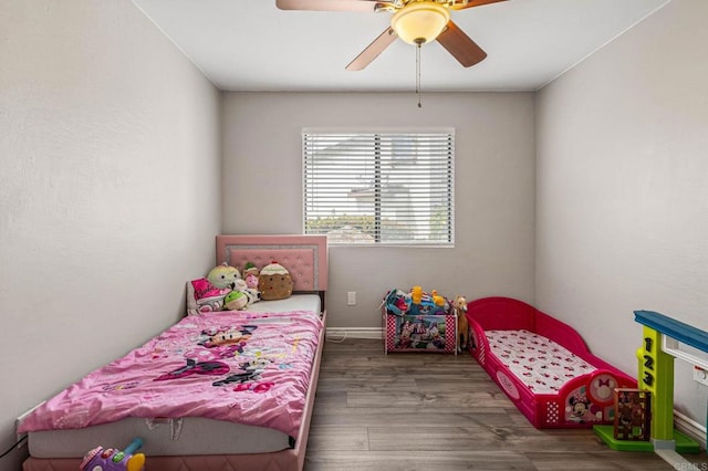 bedroom with a ceiling fan, wood finished floors, and baseboards