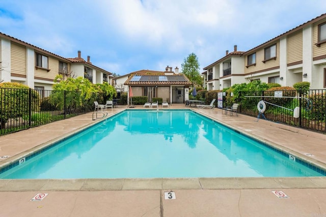 community pool with a residential view, a patio, and fence