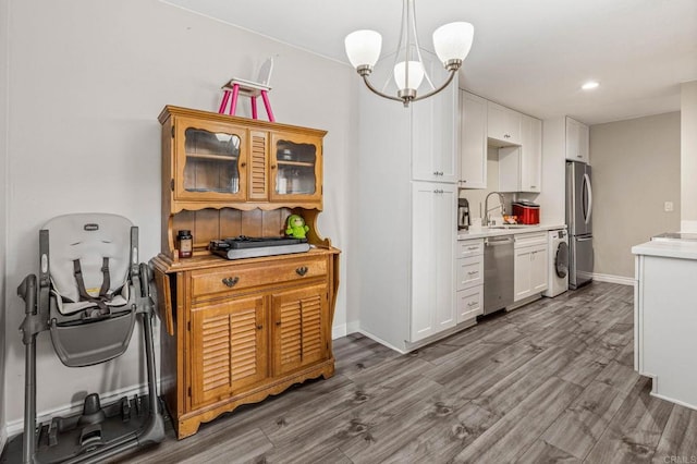 kitchen with a sink, washer / clothes dryer, dark wood-style floors, appliances with stainless steel finishes, and light countertops