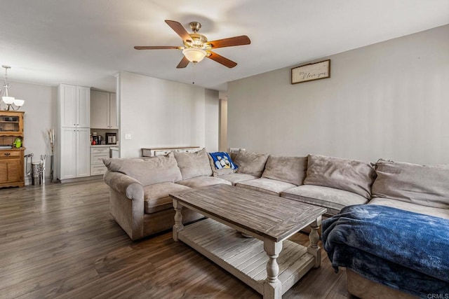 living room featuring ceiling fan with notable chandelier and dark wood-style flooring