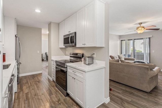 kitchen with dark wood-style floors, appliances with stainless steel finishes, open floor plan, and white cabinets