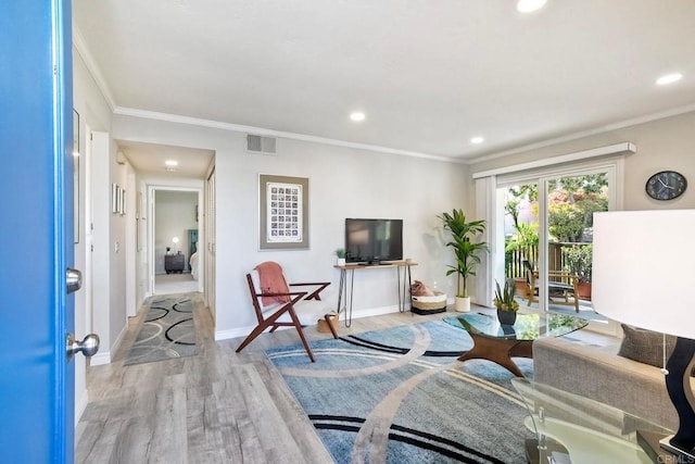 living area with visible vents, baseboards, wood finished floors, and crown molding