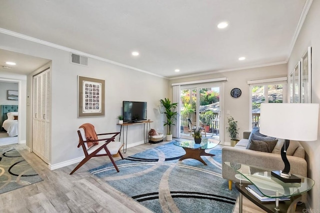 living room with crown molding, wood finished floors, visible vents, and baseboards