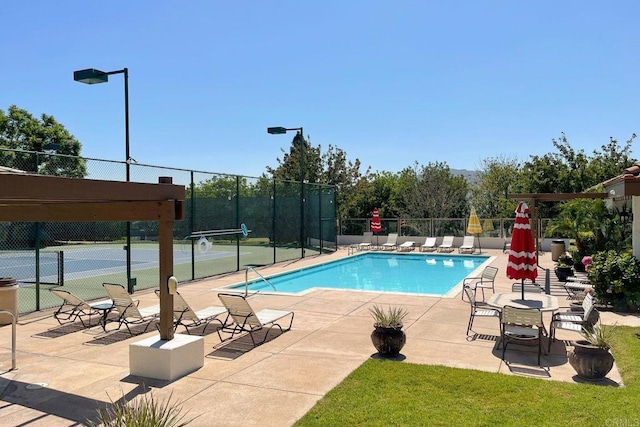 pool featuring a patio area, fence, and a tennis court