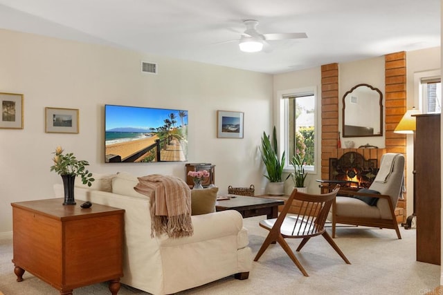 living area with a wealth of natural light, visible vents, carpet, and ceiling fan